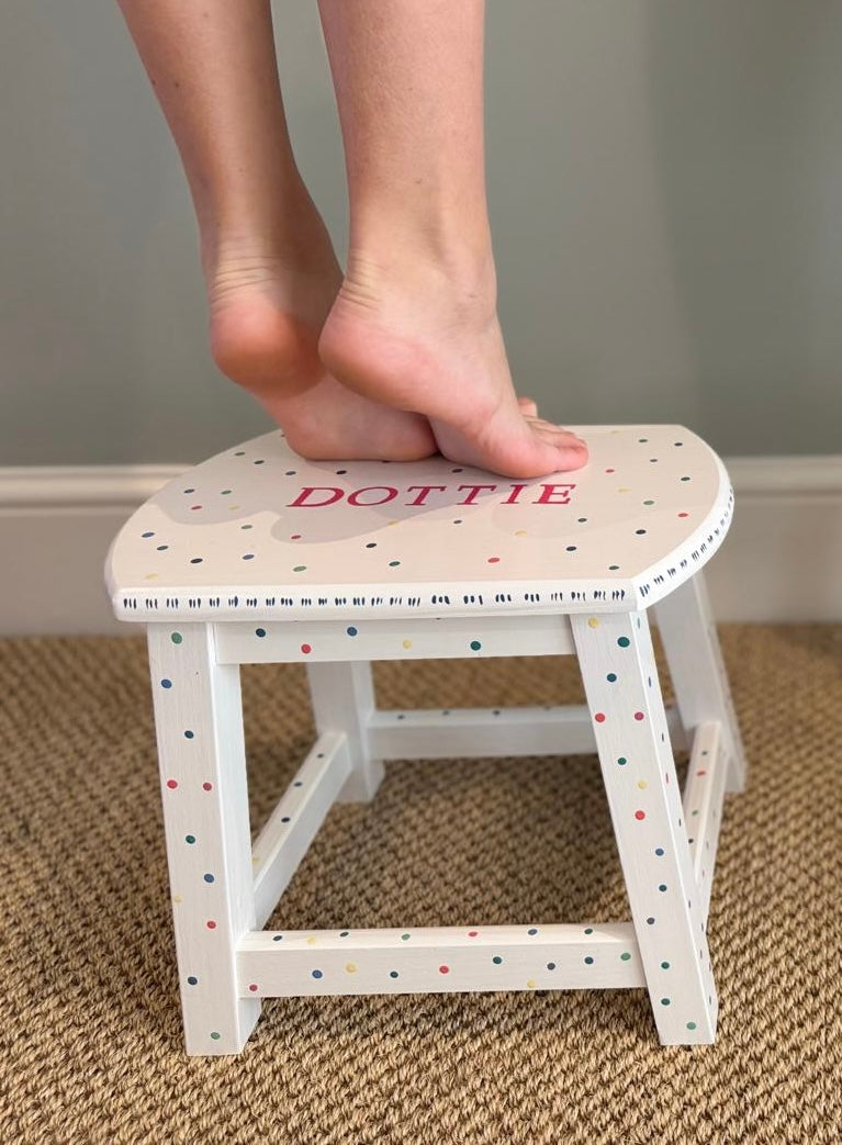 Small stool with 'Dottie' on top, child's feet stepping onto it.