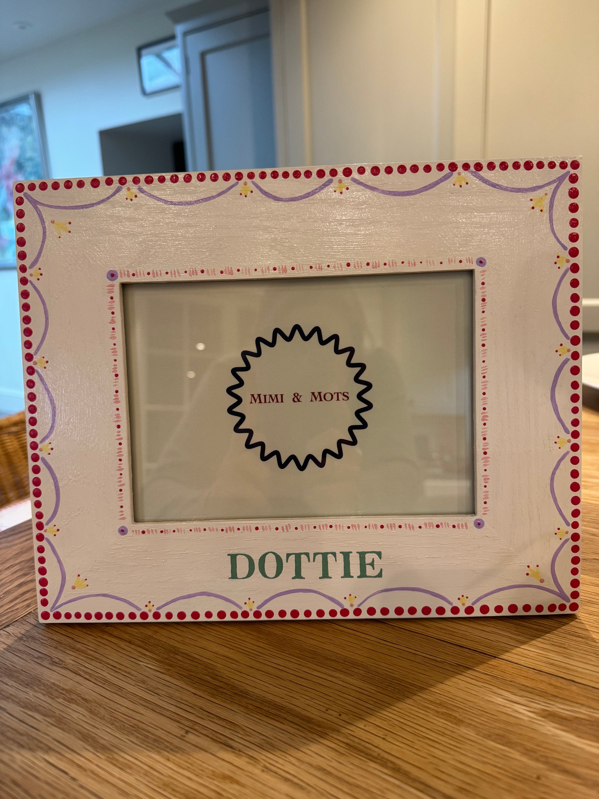 Decorative picture frame with 'Dottie' branding on a wooden surface