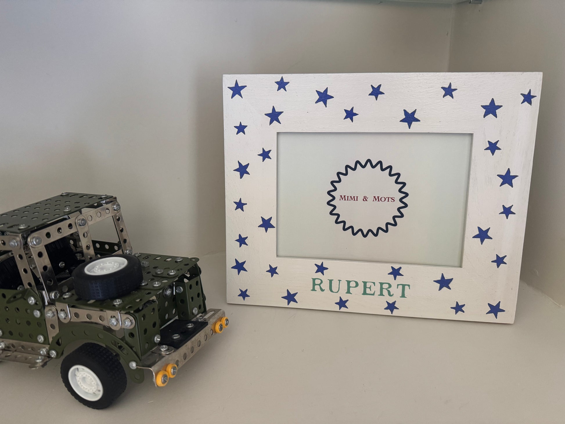 Model truck next to a personalized photo frame with blue stars and 'Rupert' text.