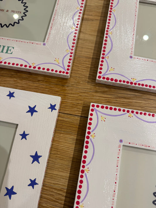 Close-up of hand-painted girls photo frames showing red polka dot and lilac scallop border detail alongside a blue star design frame – Mimi & Mots